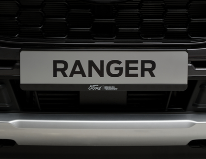 Ford registreringsskylthållare svart, med vit Ford-oval och vit text ”BRING ON TOMORROW”